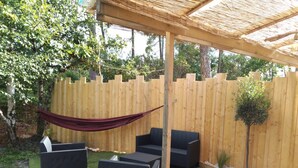A covered outdoor seating area with wicker furniture and a hammock. - Studio in the pines (Lacanau)