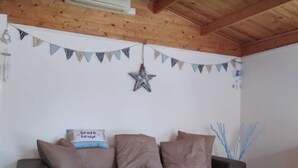 A cozy room with a wooden ceiling, a sectional sofa, and a star decoration on the wall. - Cottage a few steps from the sea (Gallina)
