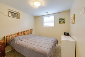 Une chambre à coucher comprenant un lit, une commode, un radiateur, une fenêtre et un four à micro-ondes posé sur un plan de travail.