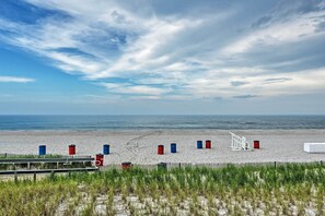Une plage avec une clôture en bois, un poste de surveillance des sauveteurs blanc et plusieurs barils.