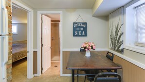 Uma sala de jantar com uma mesa e cadeiras de madeira, um vaso com flores e uma placa com a inscrição 'COTTAGE BY THE SEA'.