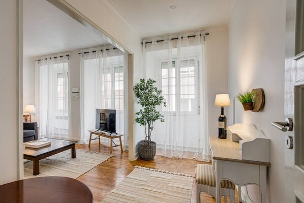 A living room with a sofa, coffee table, TV, and a potted plant.