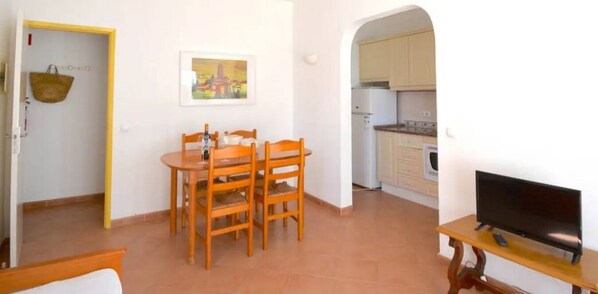 Cozy living space with a dining area, TV, and kitchen through an archway.