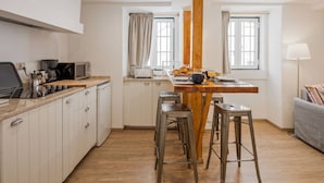 A modern kitchen with white cabinets, a wooden island, and bar stools.