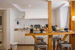 Una cocina moderna con armarios blancos, una mesa de comedor de madera y taburetes de bar.