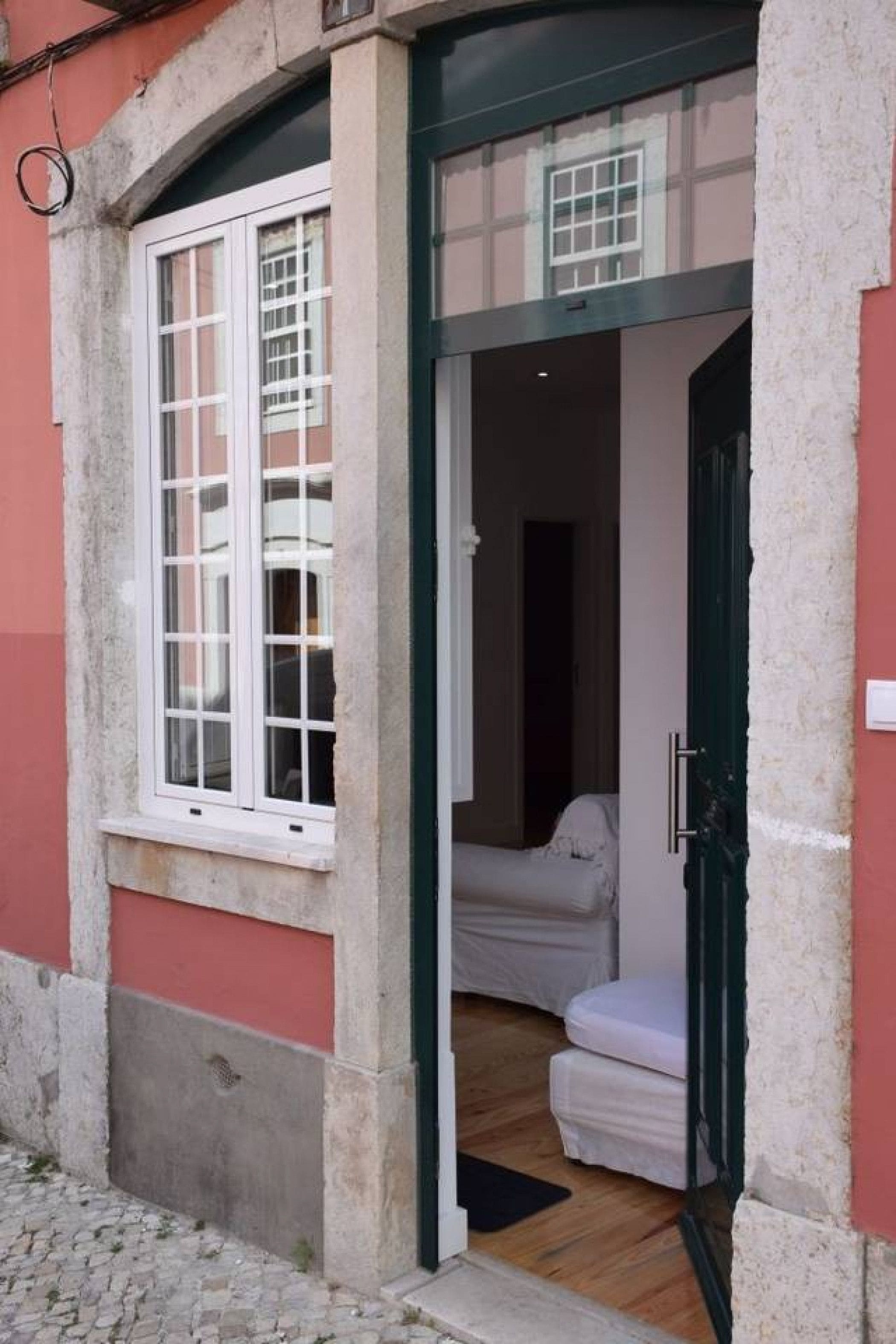 A room with a bed, a window, and a door leading to another room.