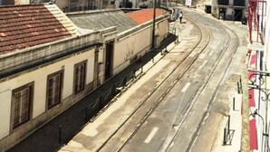Una calle con edificios, una vía tranvial y un cielo azul despejado.