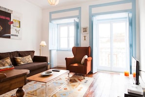 A living room with a brown sofa, a wooden coffee table, a red armchair, and a TV on a stand.