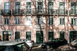 A multi-story building with balconies, a green door, and parked cars. - Flores · Cozy Tailor Made With a Refreshing Terrace (Lisboa)