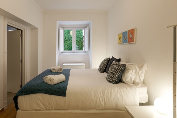 A bedroom with a bed, a window, and a door.