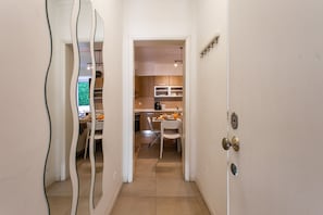 A narrow hallway leading to a kitchen with a dining area.