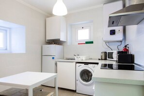 A compact kitchen with a washing machine, a microwave, and a small refrigerator.