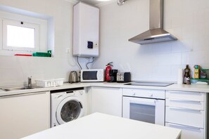 Une cuisine compacte équipée d’un lave-linge, d’un four à micro-ondes et d’un four traditionnel.