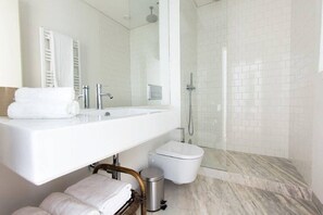 Un baño moderno con un lavamanos grande, un espejo, ducha e inodoro.