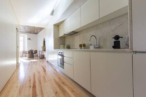 Een moderne keuken met witte kastjes, een marmeren spatwand en een houten vloer.