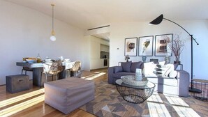 A modern living room with a sofa, ottoman, coffee table, and dining area.