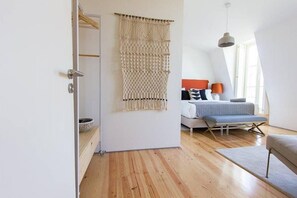 A modern living room with a wooden floor, a sofa, a coffee table, and a macramé wall hanging.