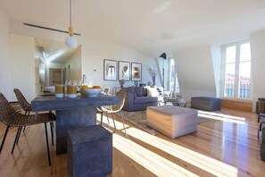 A spacious living room with a dining area, large windows, and modern furniture.