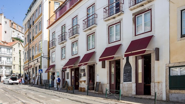 A row of buildings with awnings, a tram track, and a sign for a restaurant.