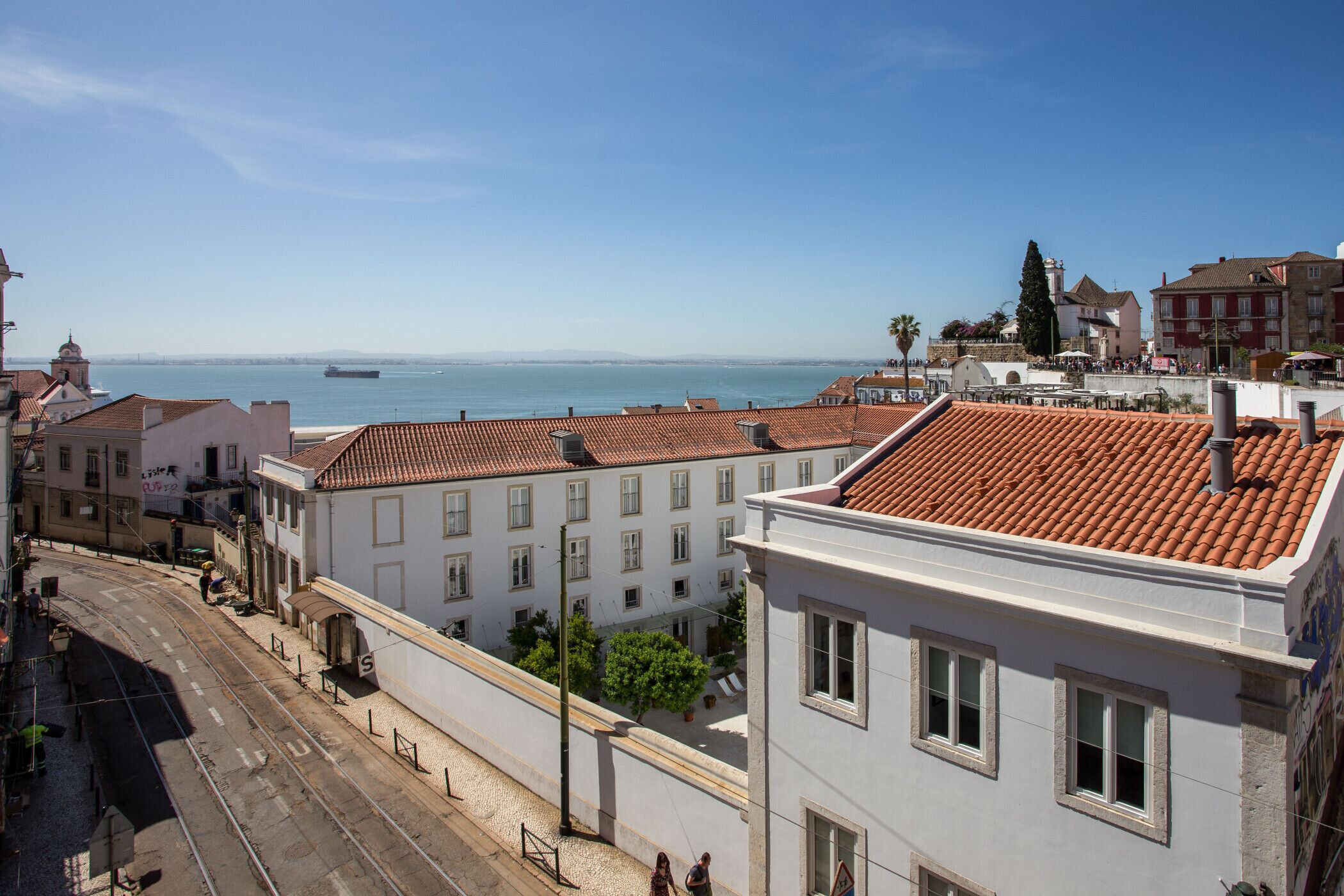 Paisagem costeira urbana com linha de elétrico, edifícios históricos e vista para o mar.