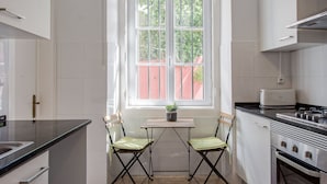 A kitchen with a window, two chairs, a table, and a stove.