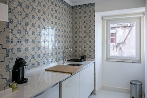 Una cocina con un lavabo, una cafetera y una ventana.