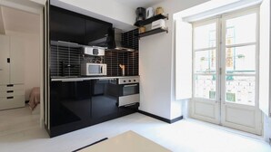 A modern kitchen with black cabinets, a microwave, and a stove. There is a window with a view of buildings outside.