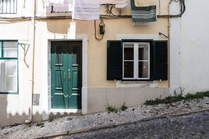 A building with a green door, a window with black shutters, and a white wall. - Metade · Charming Studio in Lisbon's Center (Lisboa)