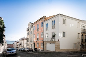 A cobblestone street lined with multi-story buildings, some with balconies and windows overlooking the street.
