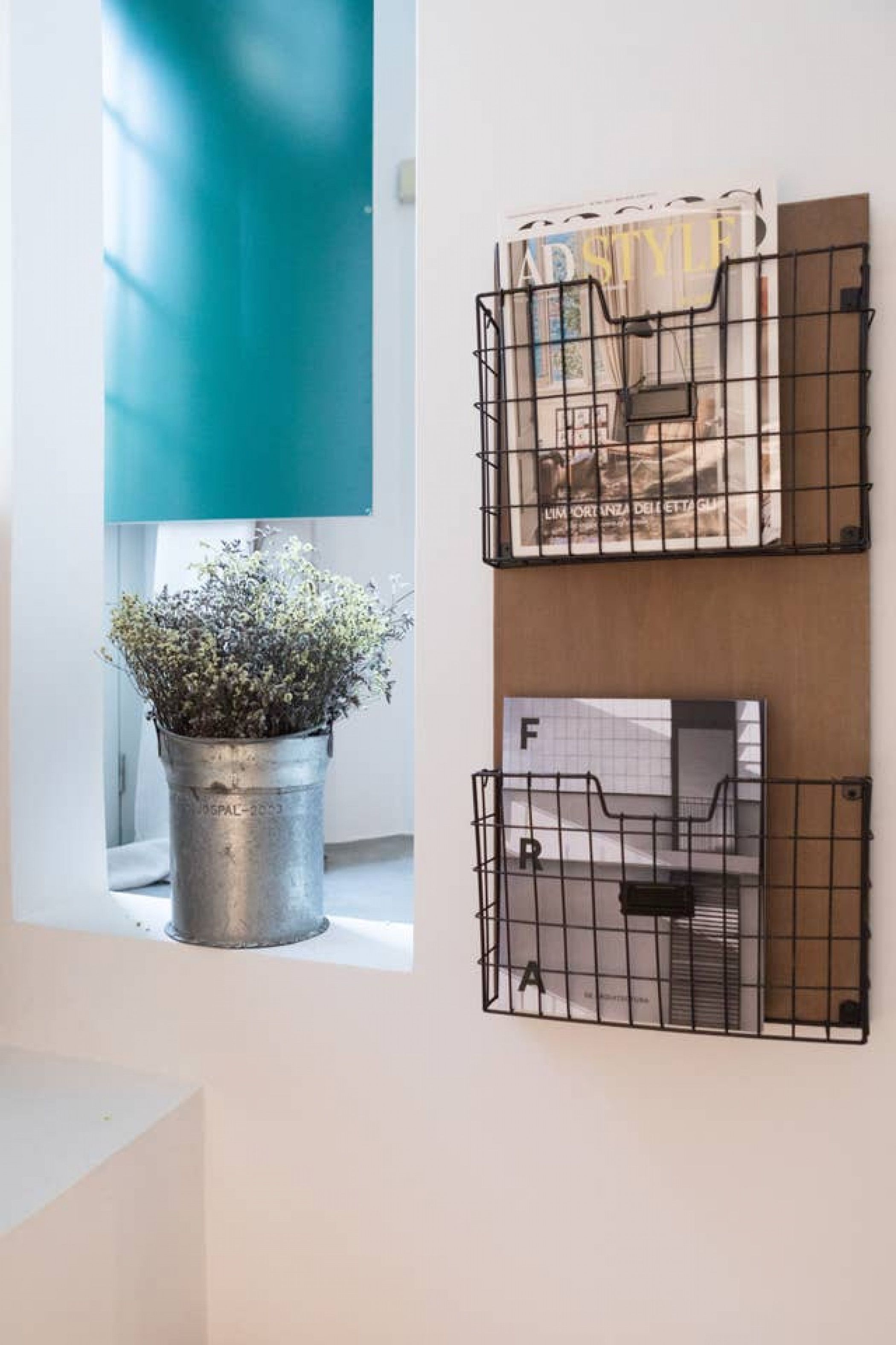Un mur orné de deux paniers en fil métallique contenant des magazines et une plante en pot.