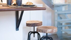 Una cocina moderna con encimera de madera, dos taburetes y una escalera.