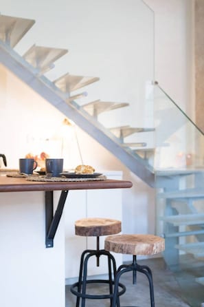 Una cocina moderna con encimera de madera, dos taburetes y una escalera.