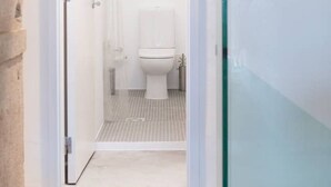 Un baño moderno con cabina de ducha de vidrio, inodoro blanco y zona de ducha visible.