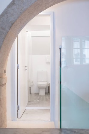 Un baño moderno con cabina de ducha de vidrio, inodoro blanco y zona de ducha visible.
