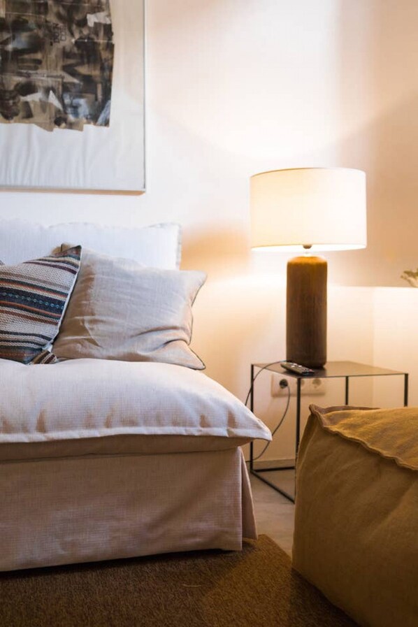 A neatly made bed with pillows, a bedside lamp, and a framed picture on the wall.