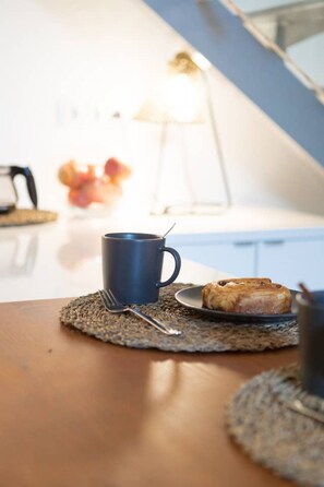 Une table mise pour le petit-déjeuner, avec une tasse, une fourchette et une pâtisserie sur un set de table.