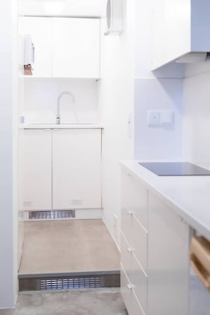 A modern kitchen with white cabinetry, a sink, and a countertop.