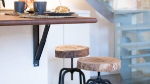 Una cocina moderna con encimera de madera, dos taburetes y una escalera.