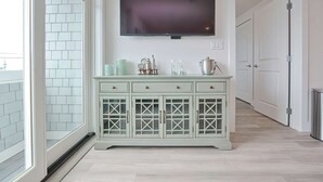 A hallway with a light green cabinet, a flat-screen TV mounted on the wall, and a door at the end. - Premier Ocean View Corner Condo (875S.F.) (Plymouth)