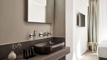 A modern bathroom with a large vessel sink, a mirror, and a toilet.