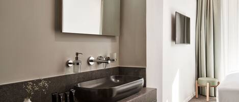 A modern bathroom with a large vessel sink, a mirror, and a toilet.