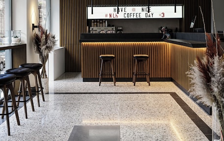 A modern bar area with a neon sign, two stools, and a coffee machine.