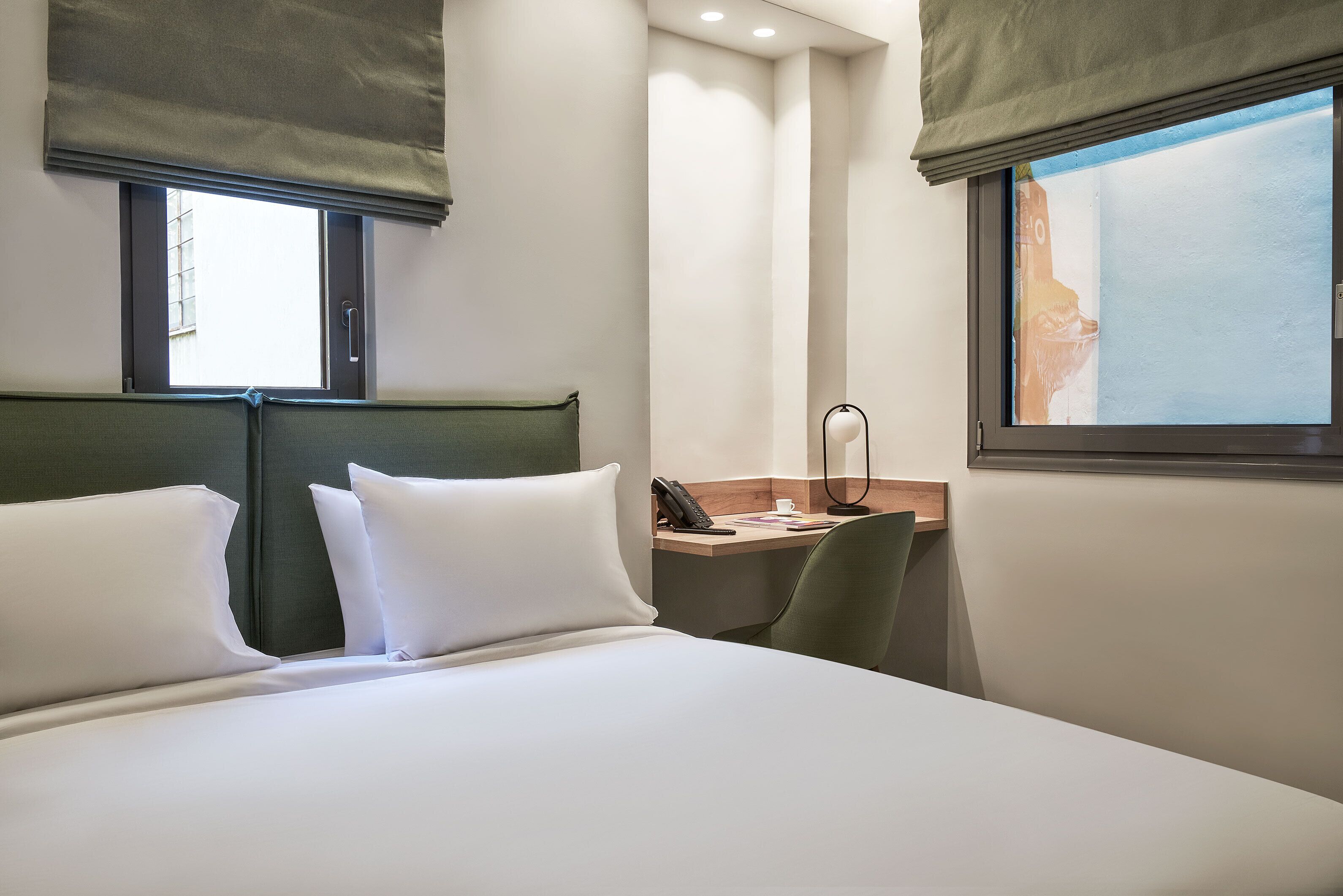 Una habitación de hotel con cama, escritorio y silla.