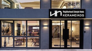 A modern hotel entrance with large glass windows, a sign reading "Neighborhood Lifestyle Hotels KERAMEIKOS," and a visible interior with seating and decor. - NLH KERAMEIKOS - Neighborhood Lifestyle Hotels (Athens)