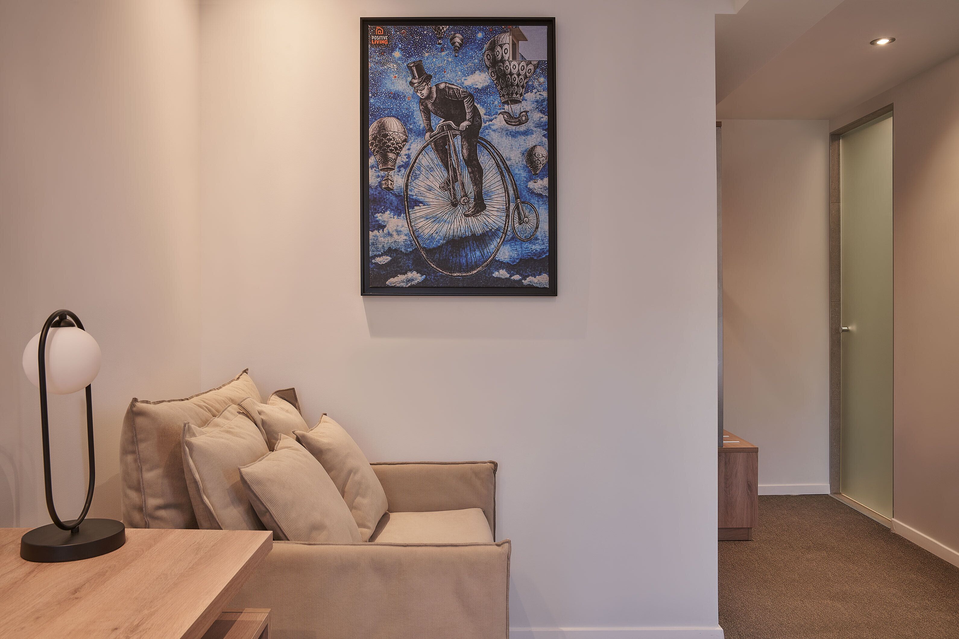 A modern room with a sofa, a framed artwork, and a lamp.