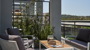 A balcony with a view, furnished with a table, chairs, and a potted plant. - NLH KERAMEIKOS - Neighborhood Lifestyle Hotels (Athens)
