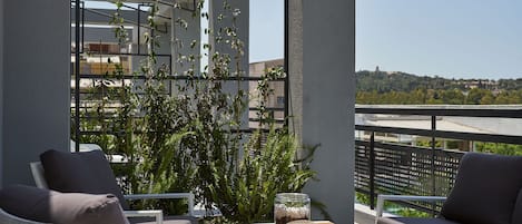A balcony with a view, furnished with a table, chairs, and a potted plant.