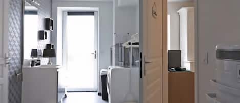 Cocina moderna con gabinetes blancos, una encimera y una lámpara colgante.