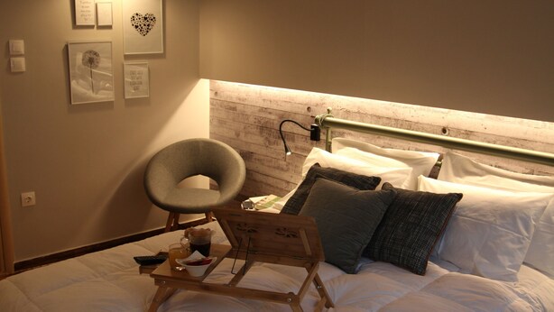 Un lit bien fait, avec une literie blanche, une tête de lit en bois et une table de chevet sur laquelle se trouve une lampe.