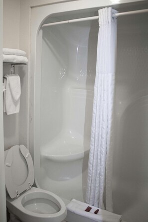 A bathroom with a toilet, a shower, and a towel rack.